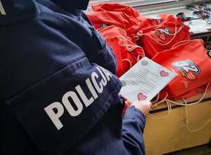 Policjantka z poradnikiem wolontariusza, w oddali czerwone worki