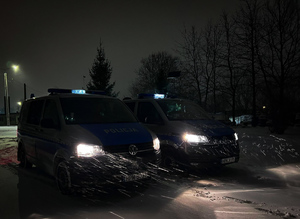 Radiowozy w nocy, pada śnieg.