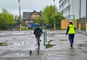 Policjantka sprawdza poprawność wykonania toru jazdy przez dziecko jadące rowerem.