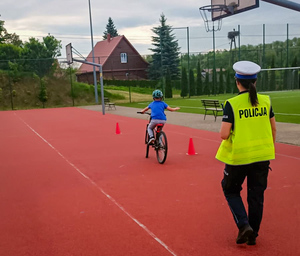 Policjantka przeprowadza egzamin na kartę rowerową, obok dziecko na rowerze.