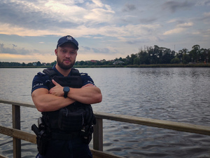 Policjant na pomoście w tle jezioro.