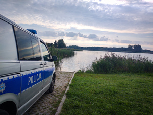 Radiowóz, w oddali jezioro.