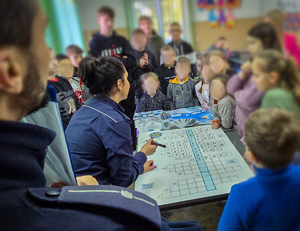 Policjanci rozwiązują z dziećmi krzyżówkę.