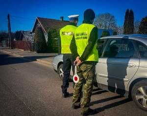 Policjant i strażnik graniczny kontrolują pojazd.