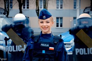 Policjantka, za nią policjanci z tarczami