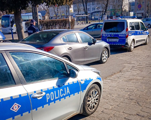 2 radiowozy i policjant stojący przy aucie osobowym
