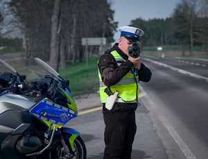 Policjant mierzy prędkość pojazdów. obok policyjny motocykl.