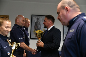 Dzielnicowy odbiera puchar.