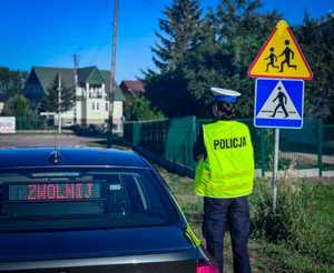Policjantka sprawdza oznakowanie w rejonie szkoły.