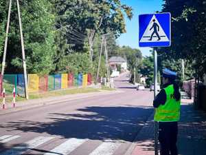 Policjantka sprawdza oznakowanie w rejonie szkoły.