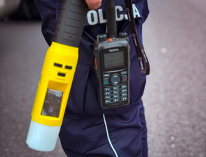 Urządzenie do badania trzeźwości w ręku policjanta obok radiostacja.