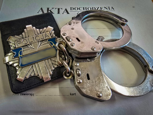 Kajdanki i gwiazda policyjna na teczce z aktami