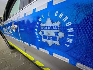 Bok policyjnego radiowozu z gwiazdą policyjną i napisem Pomagamy i Chronimy