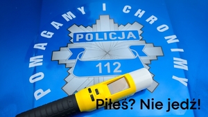 Policyjna gwiazda na masce radiowozu napis Policja i pomagamy i chronimy  i urządzenie do badania stan u trzeźwości. 
Pod spodem napis Piłeś? Nie jedź!