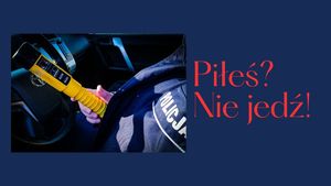 Urządzenie do badania trzeźwości w ręku policjanta i napis Piłeś? Nie jedź!