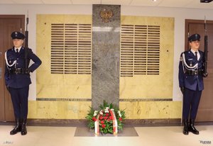 Policjanci z długą bronią przy tablicy pamiątkowej