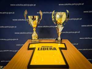 Dwa puchary i koszulka z napisem Koszulka lidera.