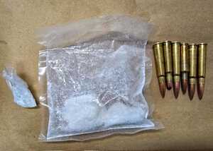 biały zbrylony proszek w foliowych torebkach i amunicja