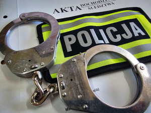 Napis policja, kajdanki i teczka z aktami.