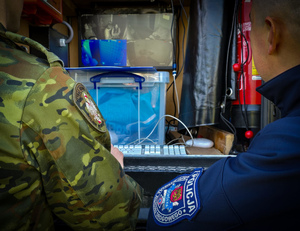 Policjant i strażnik graniczny przed nimi ekran monitora