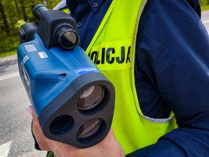 Policjantka trzyma urządzenie do mierzenia prędkości.